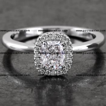 halo ring with a central cushion cut surrounded by accent stones in castle pavé setting mounted on a bird-shaped or hollow V on a slightly convex band set with a small diamond on the side (compatible with a wedding ring)