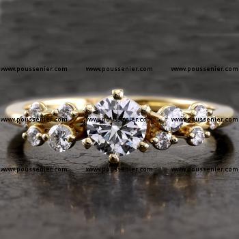 Handmade solitaire ring with a central brilliant cut diamond set with six prongs and decorated with side stones of different sizes set with two prongs or grains on a narrow thinner band