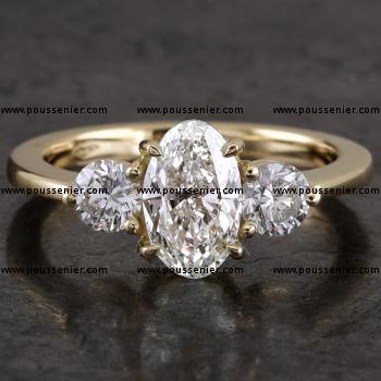 handgemaakte trilogy ring met centrale ovaal geslepen diamant met druppelgriffen gezet waarnaast twee briljant geslepen diamanten gezet met 3 griffen