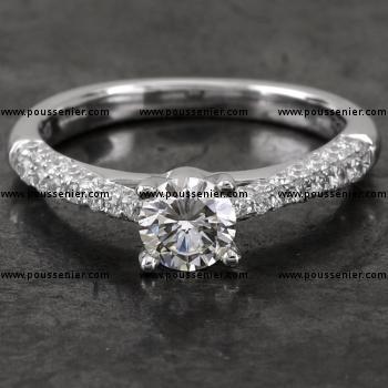 handmade engagement ring with a central brilliant cut diamond set a little higher with four slim cut prongs on a castle set band with palmettes narrowing to the top