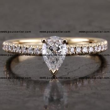 handmade solitaire ring with a pear cut diamond set with three prongs our claws made of round wire mounted on a castle set band with brilliant cut diamonds (can be worn together with wedding ring) 