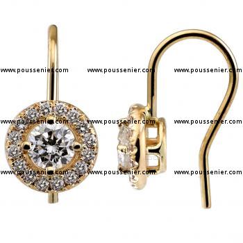 halo earrings with a central larger brilliant cut diamond accented by smaller castle set around pending on a hook system