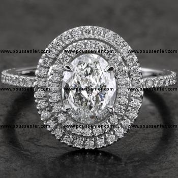 double entourage ring with an oval-cut diamond set with fine double prongs on a single fine band with rectangular profile castle pavé set with a row of smaller cut diamonds