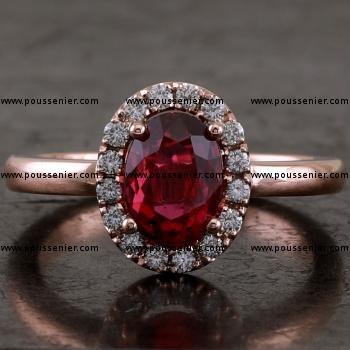 entourage ring with an oval purplish red oval ruby surrounded by brilliant cut diamonds on top of an unset shank or band with a rectangular profile slightly rounded at the top