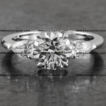 handgemaakte trilogy ring met een briljant geslepen diamant gezet met vier griffen waarnaast twee peer geslepen diamanten gezet met scheensteunpuntgriffen