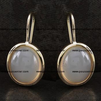 solitaire oorbellen met ovaal cabochon geslepen maanstenen gemonteerd in een ovale afgeronde zetting aan een haaksysteem