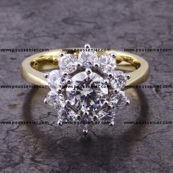 halo set entourage ring with a larger central brilliant cut diamond surrounded by smaller and set with prongs