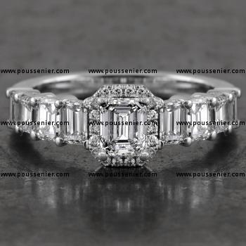 entourage ring with a central emerald cut diamond surrounded by small brilliant cut diamonds and flanked by descending emerald cut diamonds set with prongs