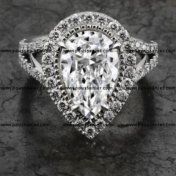 halo ring with a pear-shaped diamond surrounded by smaller millegrain and white brilliant cut diamonds