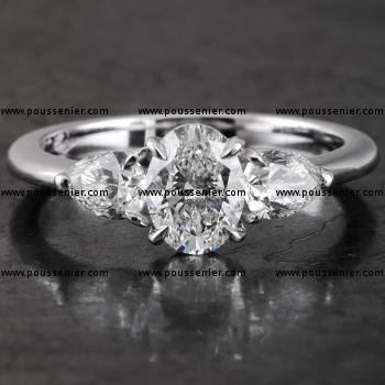 trilogy ring met een ovale diamant gezet met vier griffen waarnaast twee peer geslepen diamanten gezet met scheensteunpuntgriffen