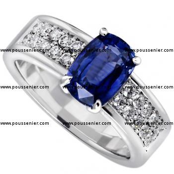 ring with a cushion cut sapphire set in four prongs between a band pavé set with two rows of brilliant-cut diamonds