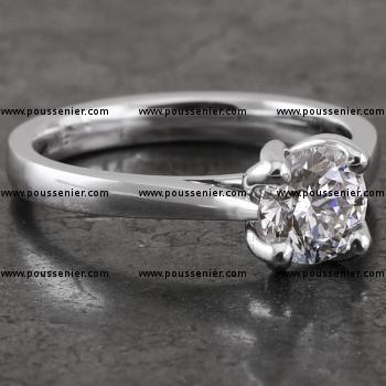 handmade solitaire ring with a larger central brilliant cut diamond set a little higher with four slim cut prongs on a band with slightly upward palmettes narrowing towards the top