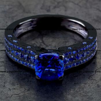 ring with a cushion cut sapphire with four prongs on a pavé set band with three rows of smaller sapphires finished with mille grain (all black rhodium plated)