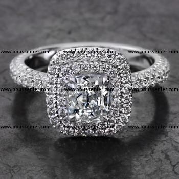 double entourage halo ring with with a cushion cut diamond set with fine prongs on a single band castle pavé set with three rows of smaller brilliant cut diamonds