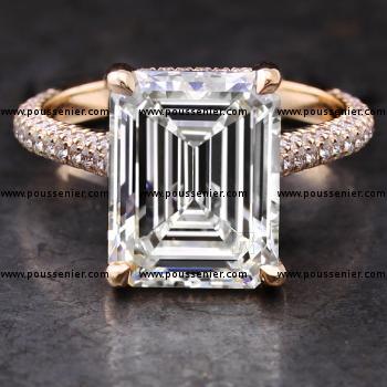 handmade solitaire ring with a central emerald cut diamond with drop shaped single prongs on a sideband set above and on the side with small brilliant cut diamonds