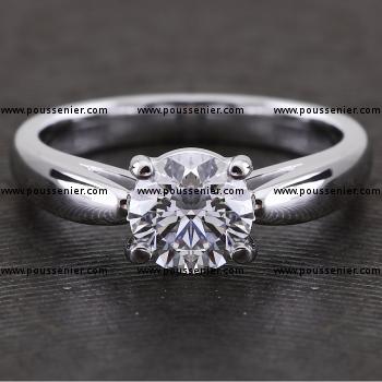 solitaire ring with a brilliant set with four prongs mounted between a slightly rounded band with palmettes