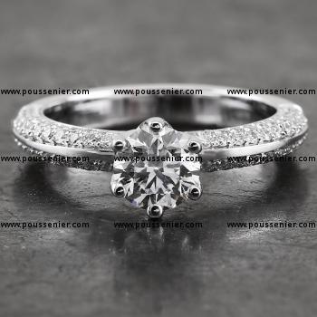 solitaire ring with a brilliant cut diamond set with six claws mounted between a band pavé set on both flanks with smaller diamonds