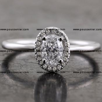 halo ring with an oval cut diamond surrounded with smaller brilliant cut diamonds on an unset shank with a round profile