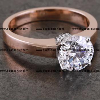 handmade solitaire ring with a brilliant cut diamond set with four round prongs mounted on a intermediate roundel set with brilliant cut diamonds on a slim band