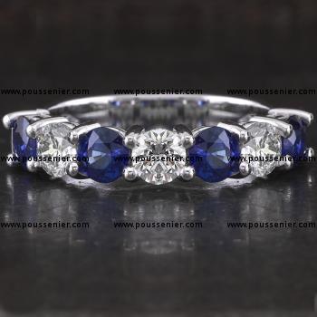 anniversary ring with three larger brilliant cut diamonds and four heat treated Ceylon sapphires set with two prongs on double roundels