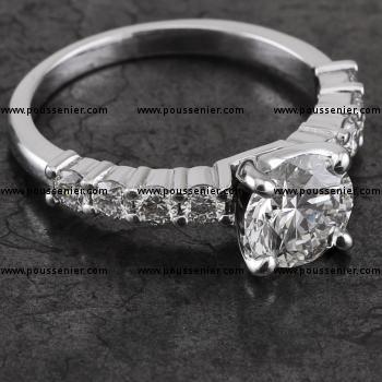 solitaire ring with a larger central brilliant cut diamond with four diamonds on the left and right, set with two prongs between two diamonds