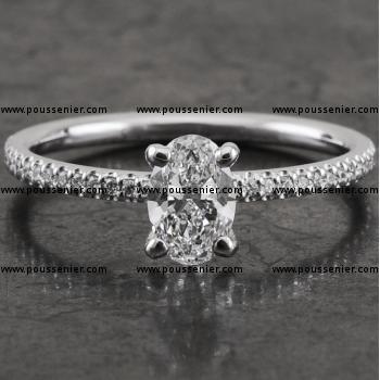 ring met een ovaal geslepen diamant gezet met vier ronde griffen op een bandje met een rond profiel kasteel pavé bezet met kleine briljant geslepen diamanten