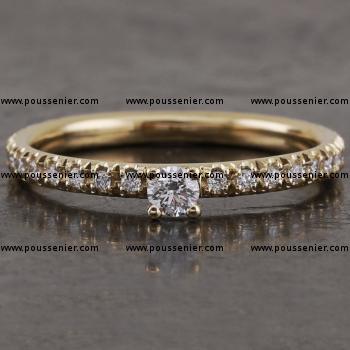 solitaire ring with a central brilliant cut diamond set in four prongs mounted on a band with a round profile castle set with small brilliant cut diamonds