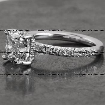 handmade engagement ring with a cushion cut diamond set with four pleated prongs made with round wire with the roundel set to the side with smaller brilliant cut diamonds