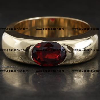 rounded ring with an oval cut ruby integrated in the band with open sides and decreasing in height downwards