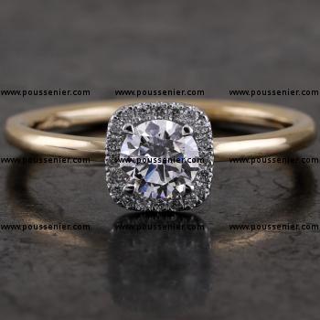 Halo ring with a central brilliant cut diamond with a cushion shaped entourage with castle set diamonds