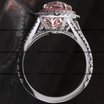 double entourage ring with an oval sapphire in a pink rondel surrounded with fancy light brilliant cut diamonds and with a second rondel with white brilliants mounted on a split band with integrated french lily logo on the side