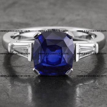 handmade engagement ring with a cushion cut ceylon sapphire set with four flatter prongs flanked by taper cut diamonds set with two bars 