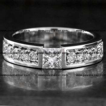 strakke solitairering met een princess geslepen diamant waaronder een klein bruggetje en waarnaast kleinere pavé gezette diamanten afgewerkt met een gravure