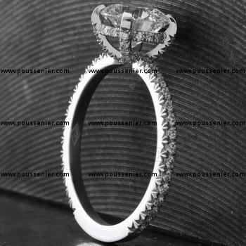 Ring met een grotere briljant geslepen diamant gezet met vier bezette griffen op een bandje met een rechthoekig profiel kasteel fishtail pavé bezet met kleine briljant geslepen diamanten