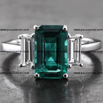 ring met een smaragd of emerald geslepen Zambiaanse smaragd waarnaast twee baguette geslepen diamanten mee in de lengte gezet met griffen