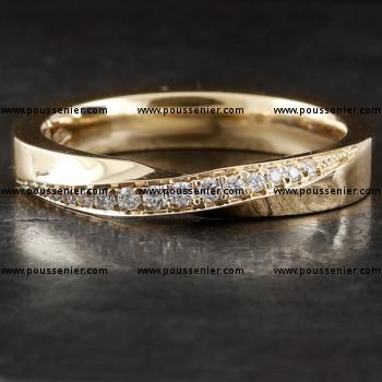 handmade möbius wedding ring with twisted top and flat interior, partly pavé set with a row of brilliant cut diamonds