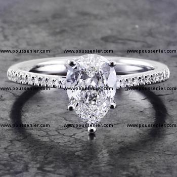 ring with a pear shaped diamond set with five claws on a rounded shank with palmets castle set with smaller brilliant cut diamonds